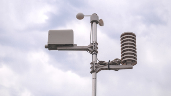 A weather station made up of a set of weather measuring instruments against a sky background